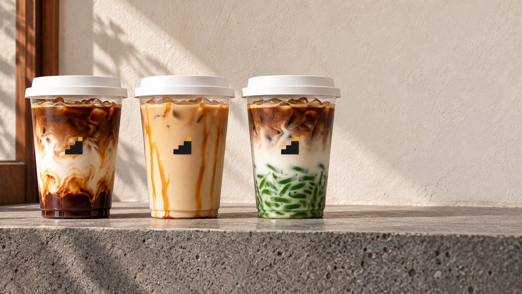 Tiga minuman signature di atas batu andesit: Es Kopi Aren, Vanilla Caramel, Pandan Cendol Latte